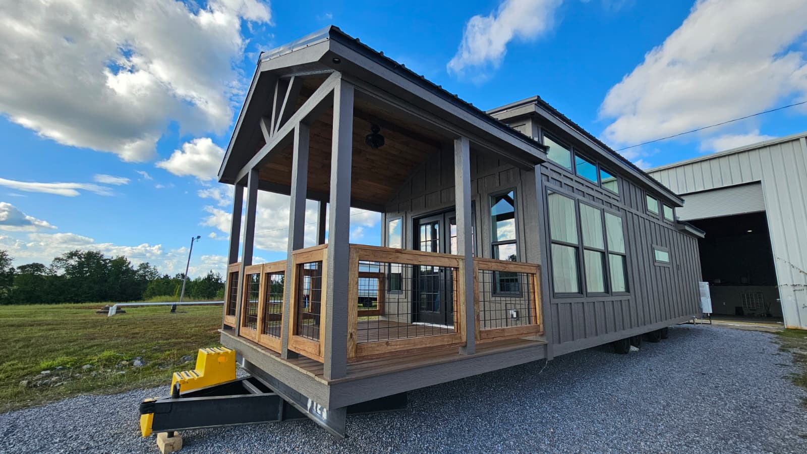 The Lodge park model home with covered porch and natural wood railings, built by Phoenix Building Solutions